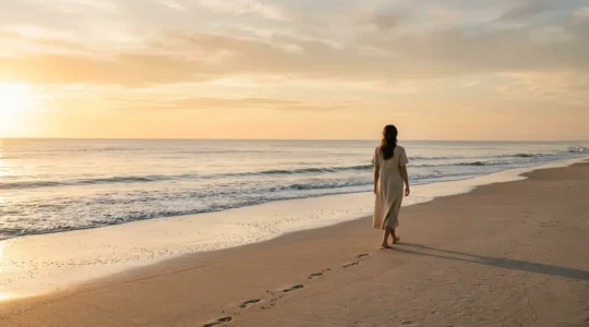 Personne marchant pieds nus sur une plage naturelle au lever du soleil, symbolisant la liberté et l'acceptation de soi