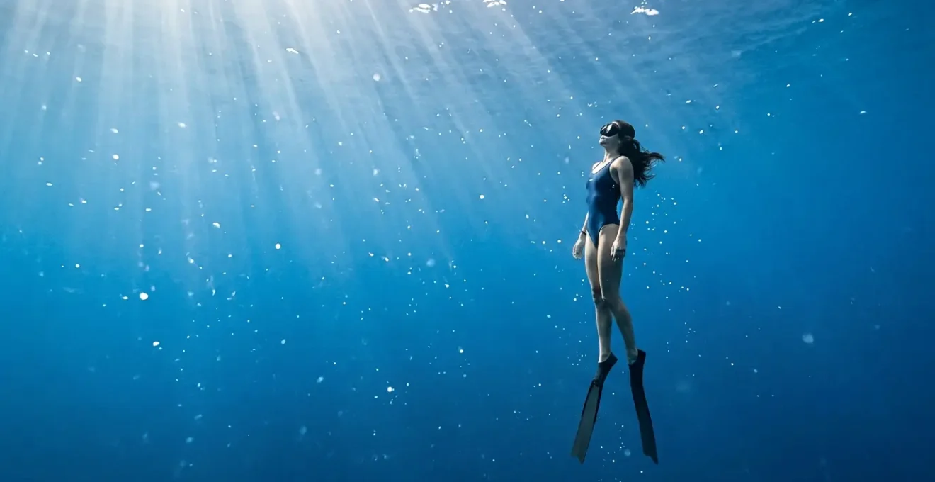 Plongeur en apnée dans une eau cristalline méditerranéenne, entouré de lumière naturelle filtrée