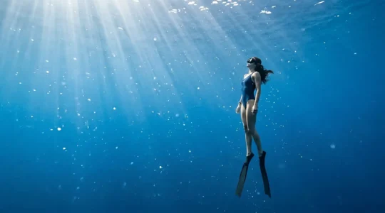 Plongeur en apnée dans une eau cristalline méditerranéenne, entouré de lumière naturelle filtrée